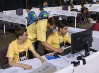 Michał Łowicki, Paweł Michalak i Tomasz Syposz siedzący w żółtych koszulkach przed monitorem.